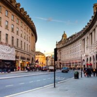 A bustling view of Regent Street in London with historic architecture and lively street life.